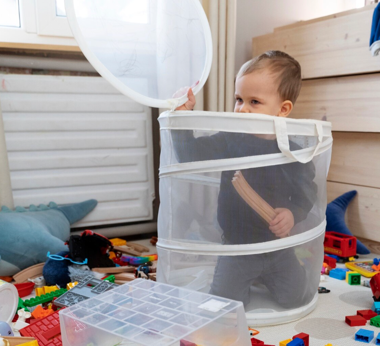 Kisfiú egy játék tároló zsákban,színes játékkockák a földön